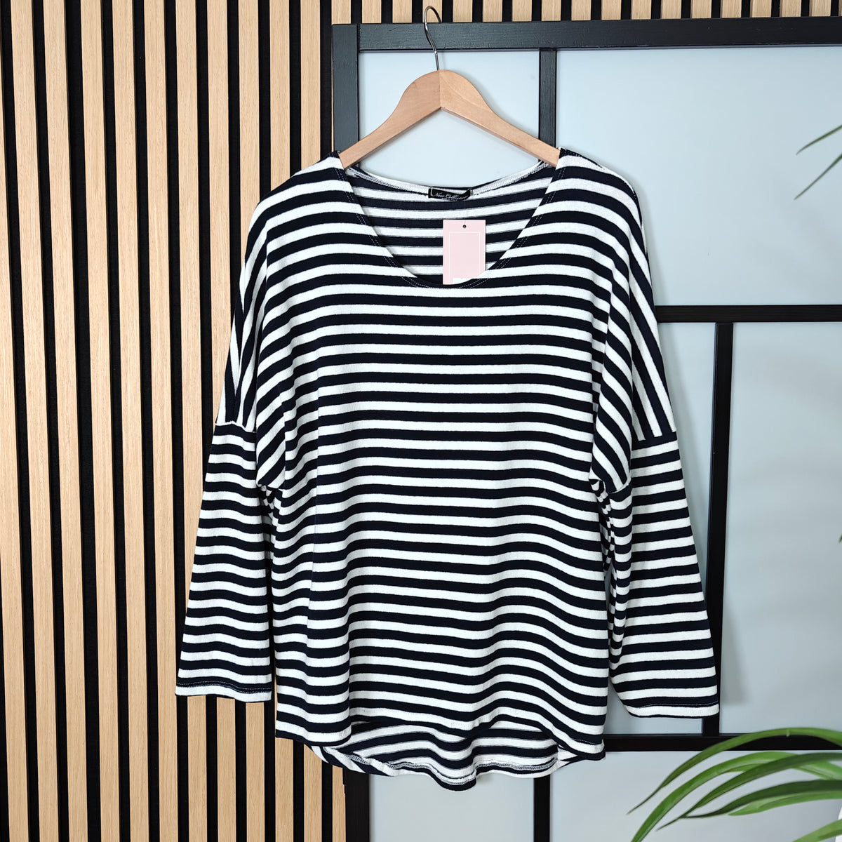 Black and white striped shirt on a hanger against a striped wall.