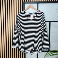 Black and white striped shirt on a hanger against a striped wall.