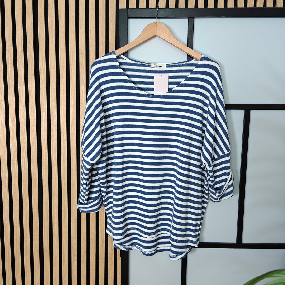 Blue and white striped shirt on a hanger against a striped wall.