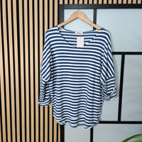 Blue and white striped shirt on a hanger against a striped wall.