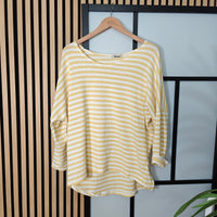 Lemon and white striped shirt on a hanger against a black and beige striped background