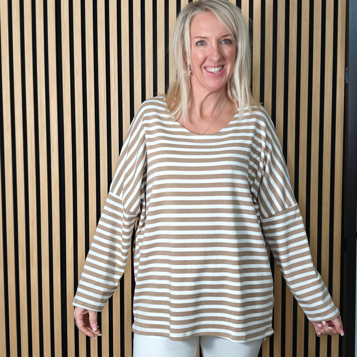 Woman wearing a striped sweater standing against a striped wall.