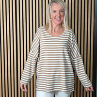 Woman wearing a striped sweater standing against a striped wall.