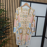Decorative dress with geometric pattern on a hanger against a striped wall.