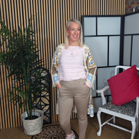 Woman standing in a room with a plant and chair, smiling.