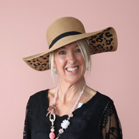 Woman wearing a wide-brimmed hat with leopard print details on a pink background