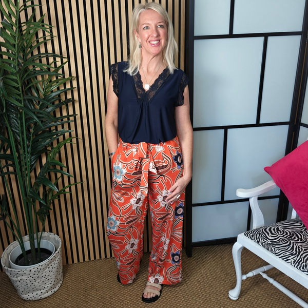 Woman standing in a room with a plant and a chair with a zebra print cushion.