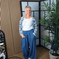 Woman standing in a room with plants and a striped wall