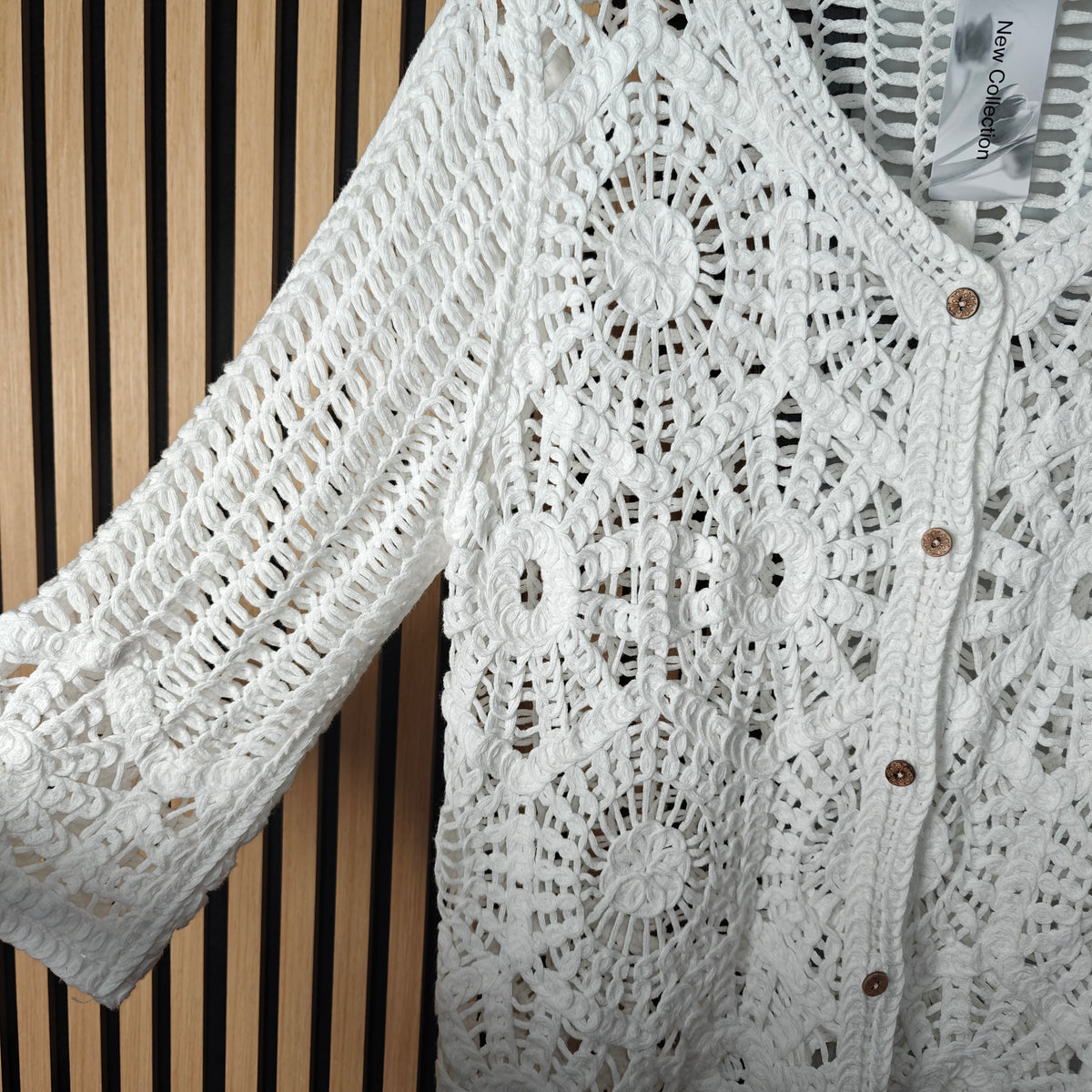 White lace cardigan with brown buttons on a striped background