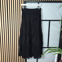 Black lace dress hanging on a rack against a striped wall.