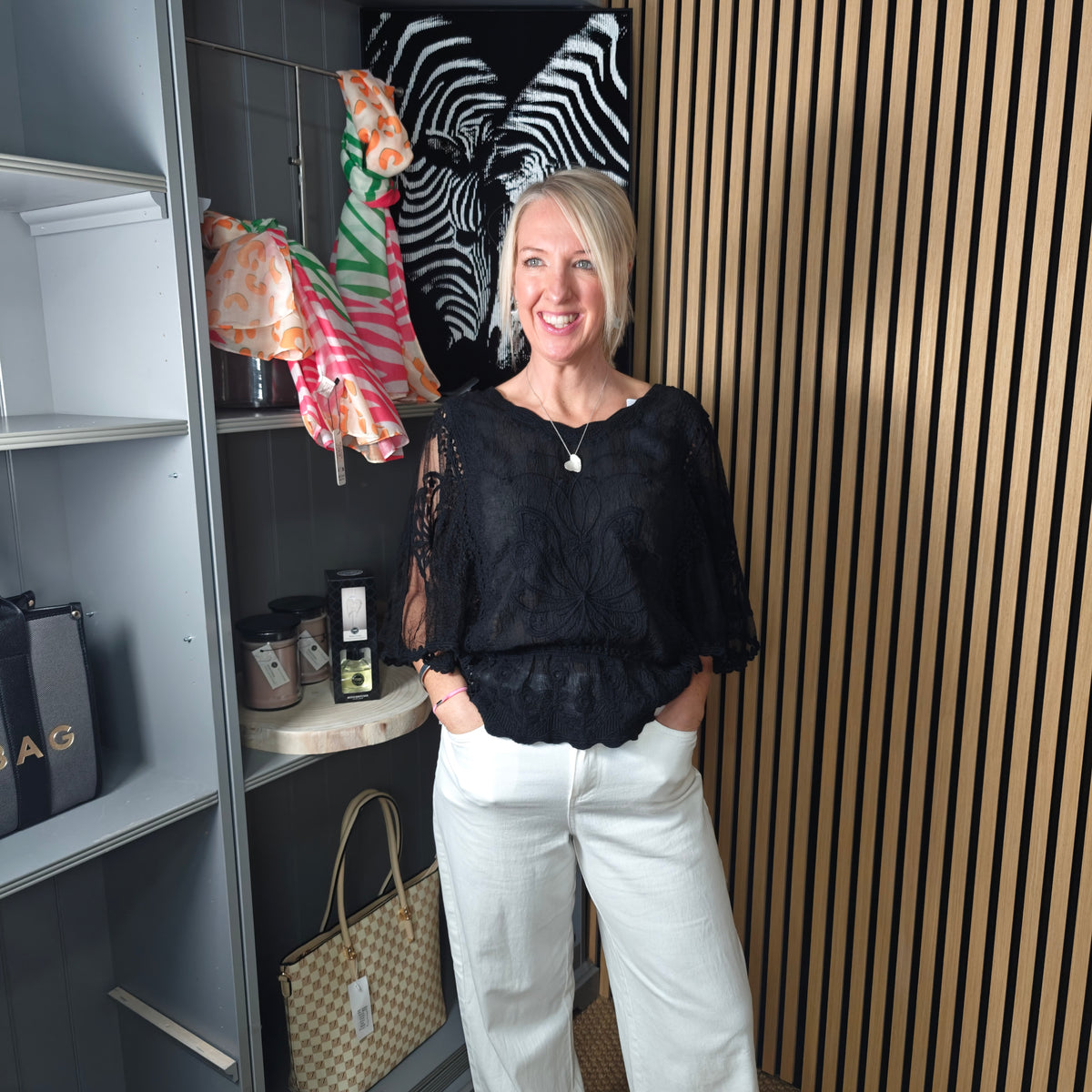 Woman standing in a room with shelves and a striped wall