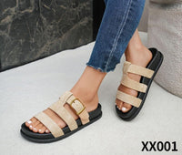 Beige sandals with black soles worn with blue jeans on a light background