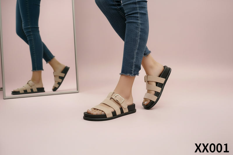 Beige sandals with black soles worn with blue jeans on a light background