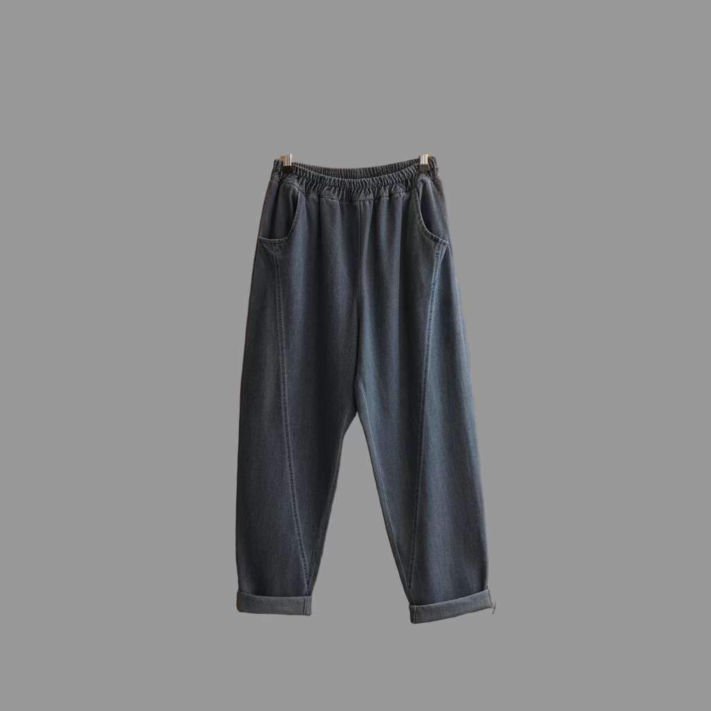 Gray sweatpants denim hanging on a hanger against a brick wall.