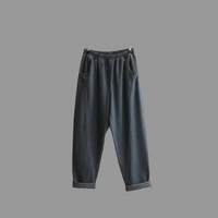 Gray sweatpants denim hanging on a hanger against a brick wall.