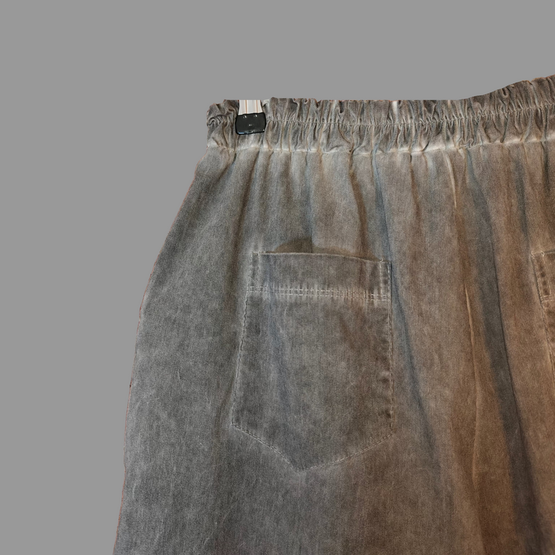 Gray pants hanging on a hanger against a brick wall.