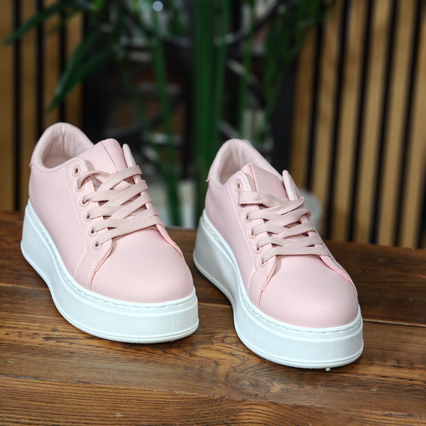 Pair of pink sneakers with white soles on a wooden surface.
