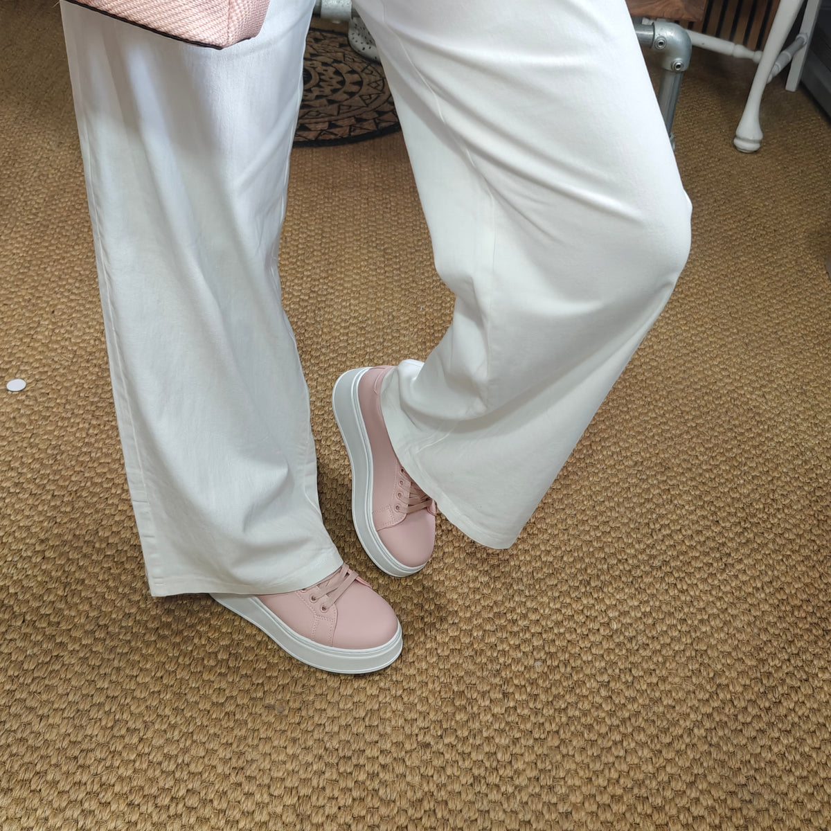 Person wearing light pink shoes and white pants on a carpeted floor.
