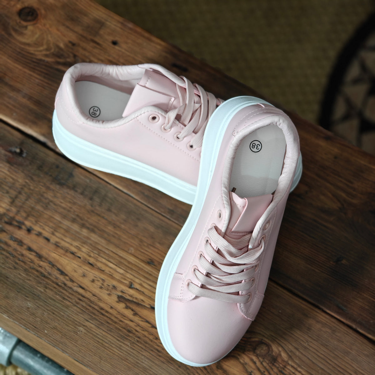 Pink sneakers with white soles on a wooden surface