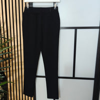 Black pants hanging on a rack against a light background