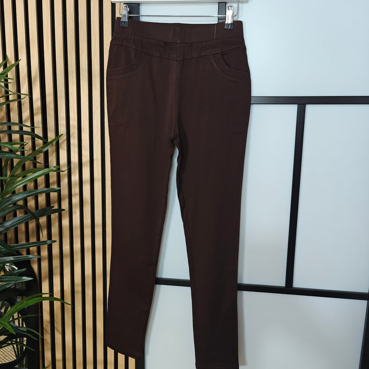 Brown pants hanging on a rack against a light background