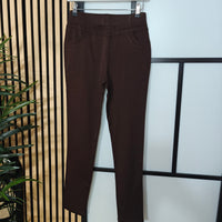 Brown pants hanging on a rack against a light background