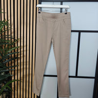 Beige pants hanging on a rack against a striped wall.