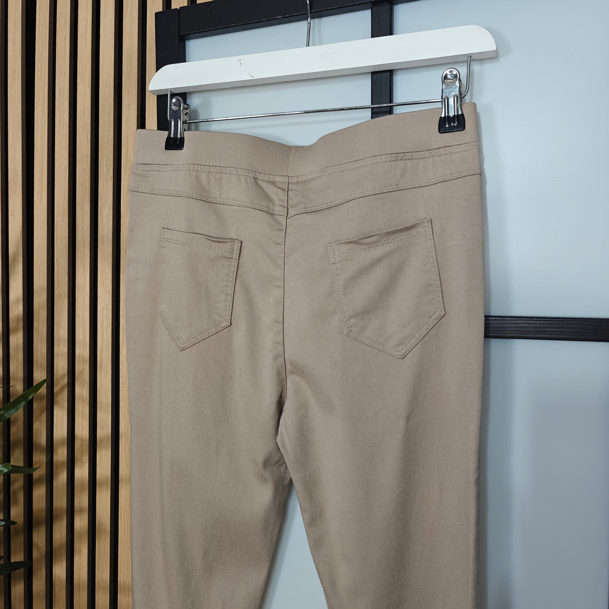 Sand pants hanging on a rack against a neutral background
