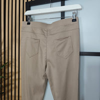 Sand pants hanging on a rack against a neutral background