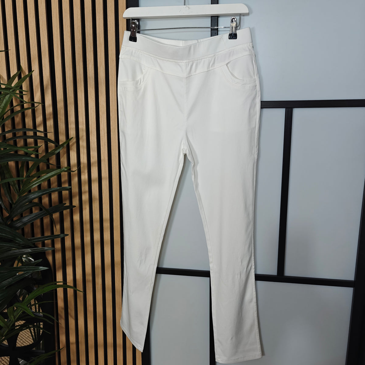 White pants hanging on a rack against a neutral background