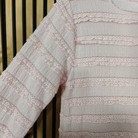 Close-up of a textured fabric with lace detailing on a wooden background