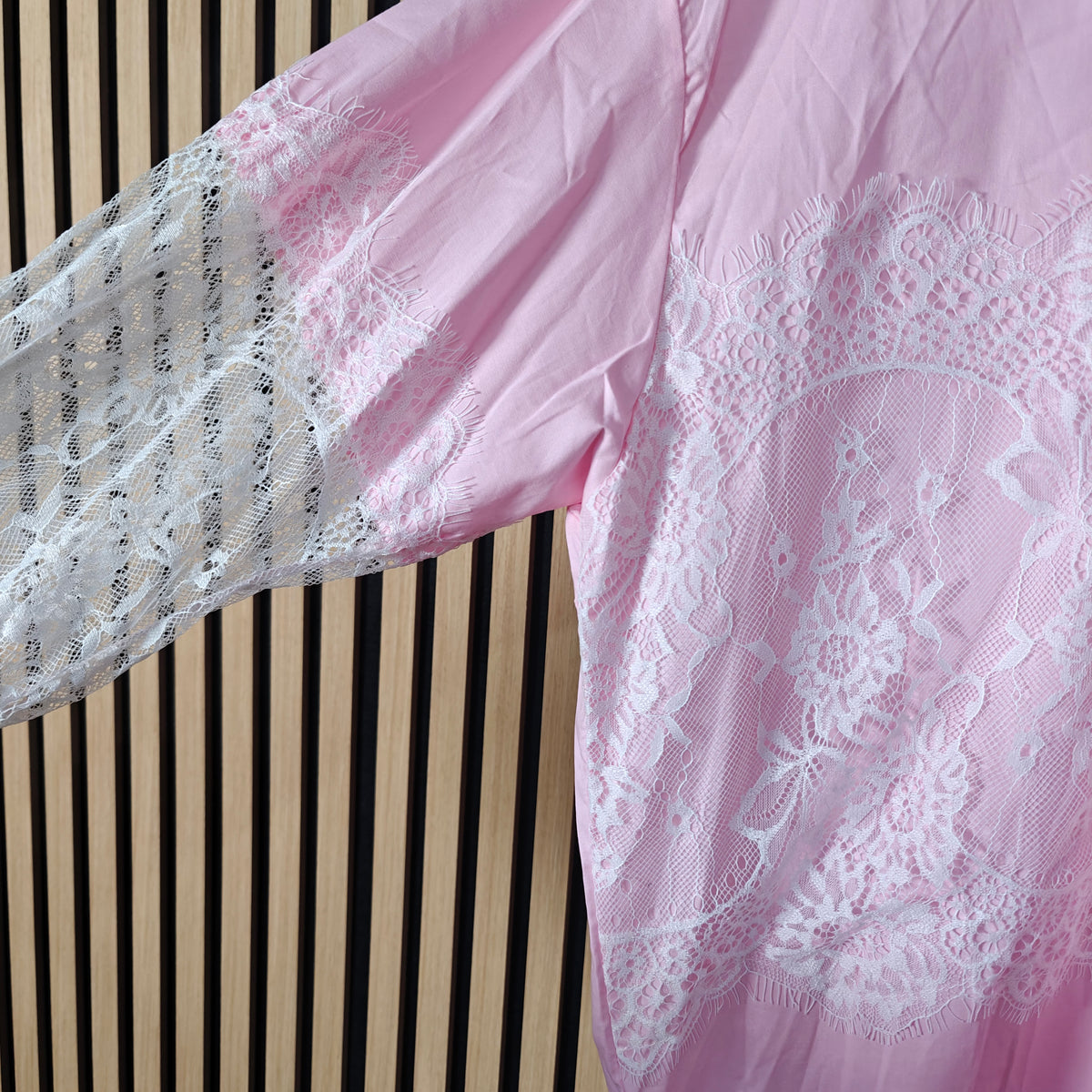Close-up of a pink lace garment against a striped background