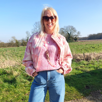Lady wearing jacket jeans and jumper standing on grass 