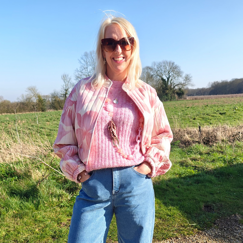 Lady wearing jacket jeans and jumper standing on grass 