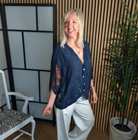 Navy lace top on lady with white trousers and trainers 