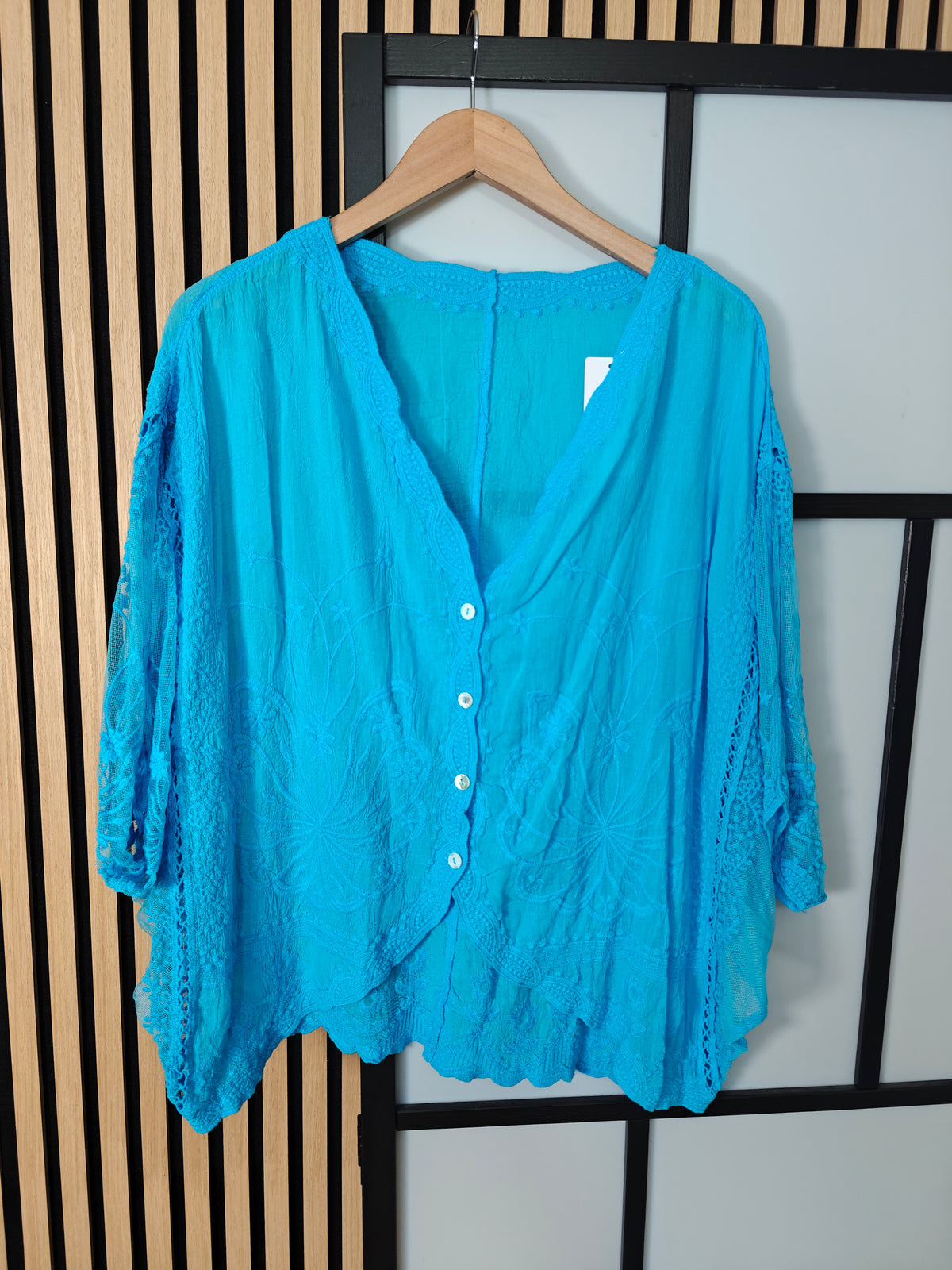 Turquoise lace top hanging on hanger 