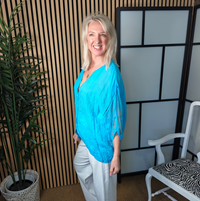 Lace turquoise top styled with white trousers and trainers 