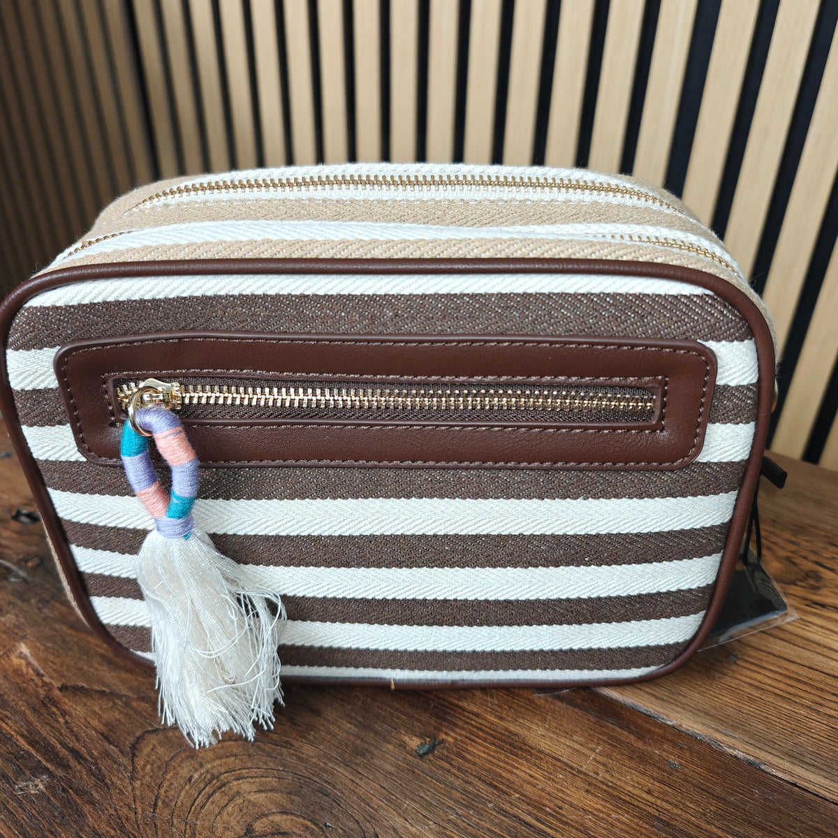 Striped bag with a tassel on a wooden surface