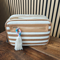 Striped cosmetic bag with tassel on a wooden surface
