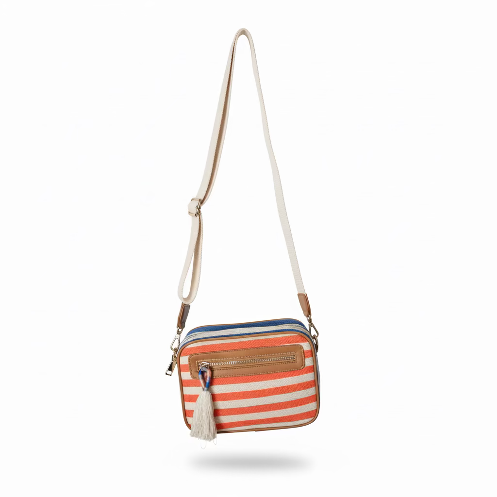 Striped crossbody bag with a tassel hanging on a wooden hanger against a light gray wall.
