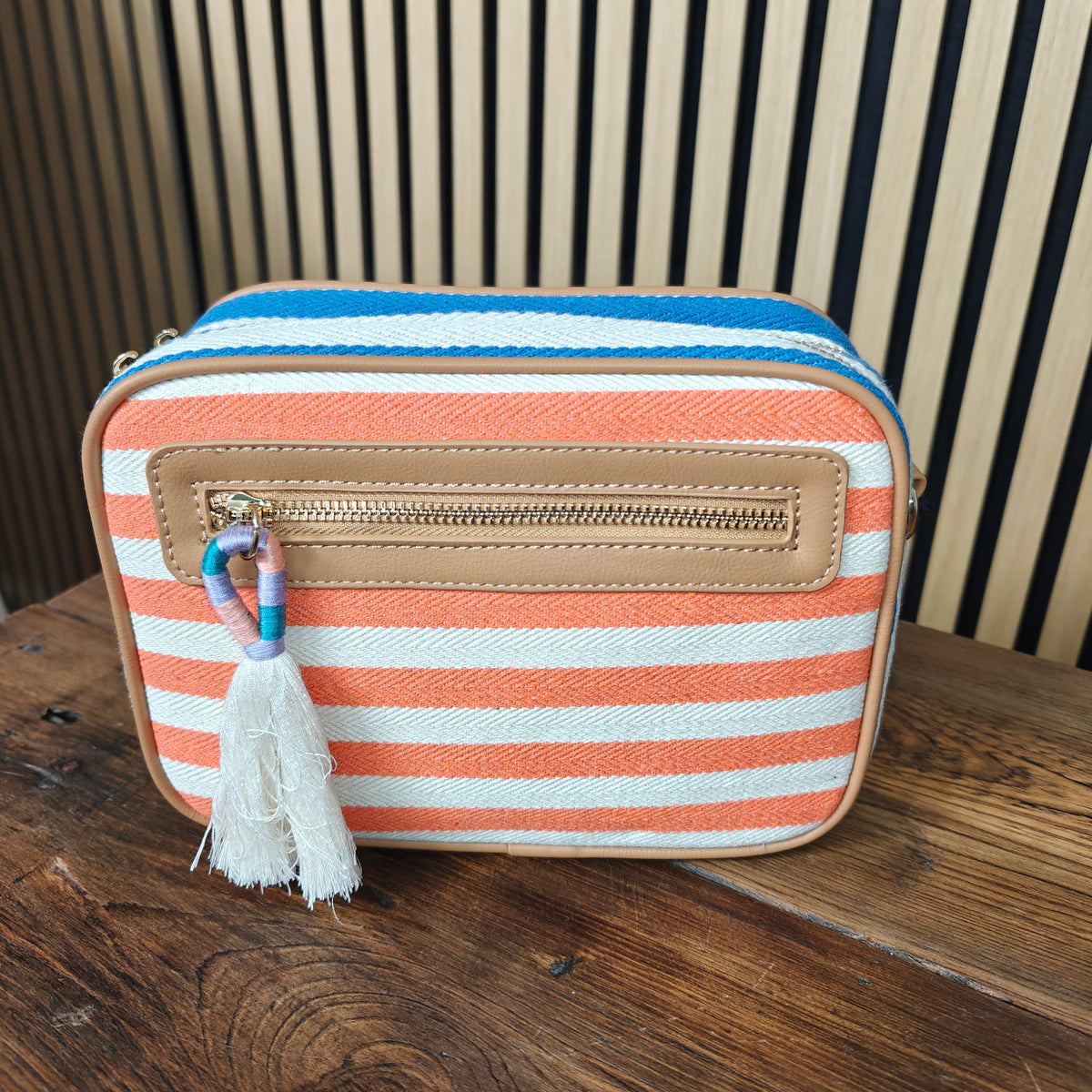 Striped handbag with tassel on a wooden surface