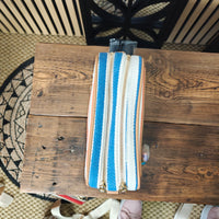 Striped pouch with gold zippers on a wooden surface