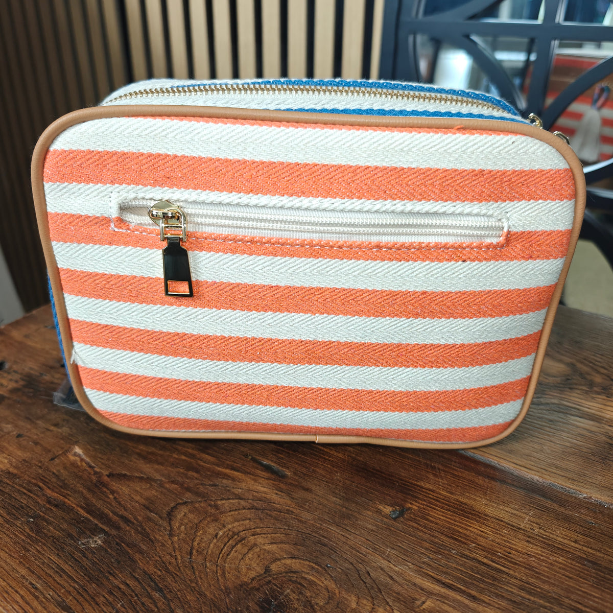 Striped pouch with orange and white stripes on a wooden surface