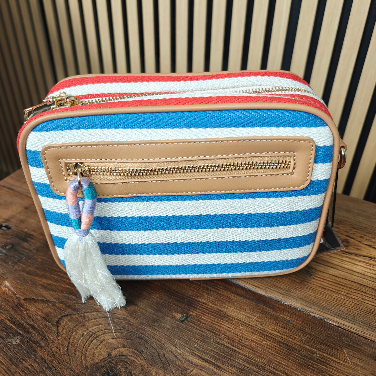 Striped purse with a tassel on a wooden surface