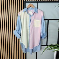 Color-blocked shirt on a hanger against a striped wall
