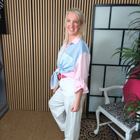 Woman in a stylish outfit posing in an indoor setting with a plant and chair.
