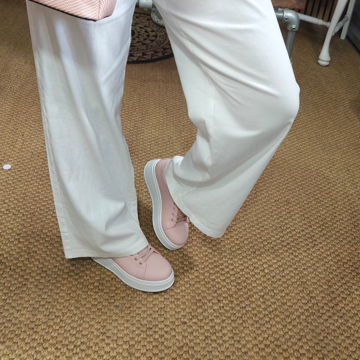 Person wearing light pink shoes and white pants on a carpeted floor.