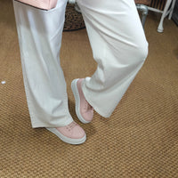 Person wearing light pink shoes and white pants on a carpeted floor.