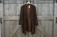 Brown jacket with a tag on a hanger against a striped wall.