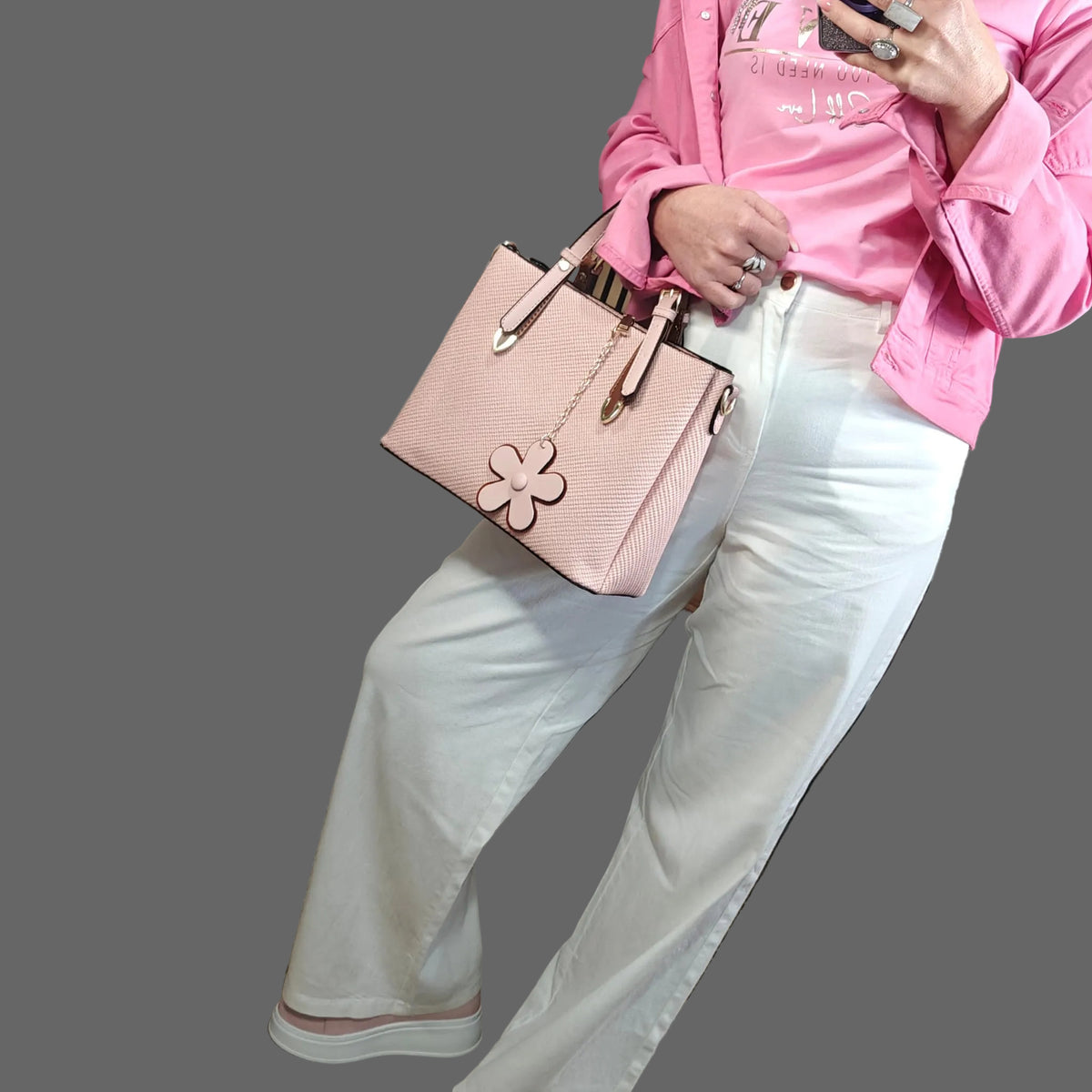 Person wearing a pink jacket and white pants holding a matching pink handbag.
